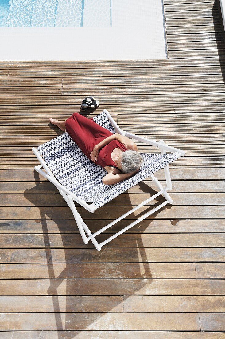 Frau entspannt sich auf Liegestuhl am Swimmingpool