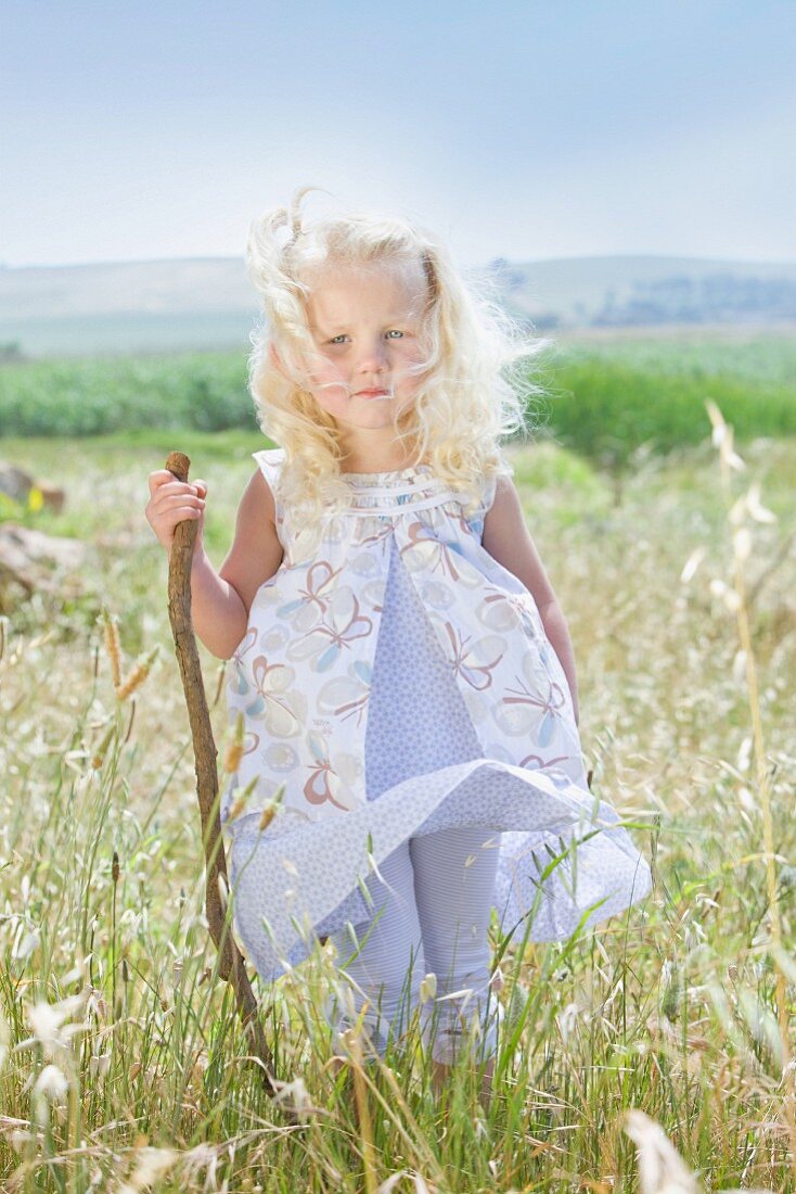 Little girl standing in summer meadow