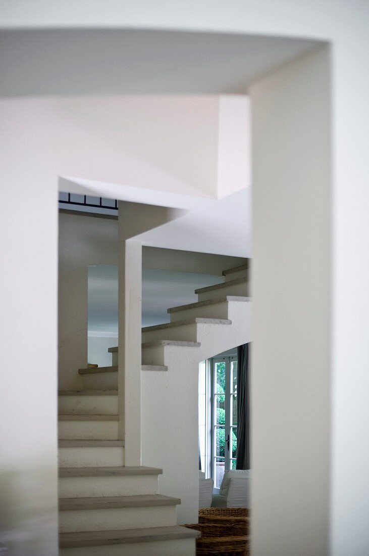 Blick durch Durchgang auf Wendeltreppe mit Trittstufen aus Stein in offenem Treppenhaus
