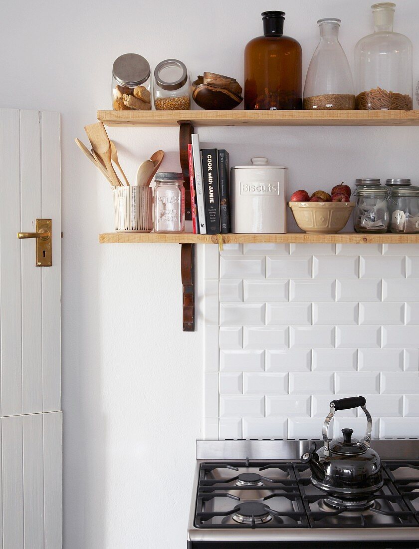 Küchenregal aus Holz mit Vorratsbehältern und Küchenutensilien über einem Retro Gasherd