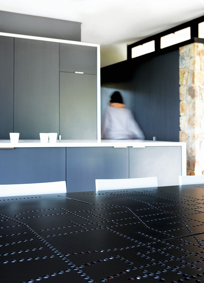 Purist, grey fitted kitchen; black table top with perforated pattern in foreground