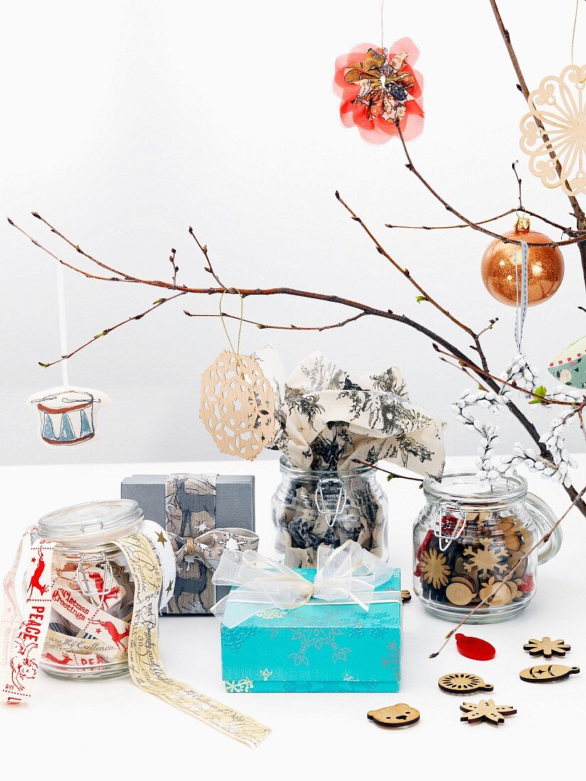 In dezenten Naturfarben weihnachtlich geschmückte Zweige, Einmachgläser mit Dekowaren und Geschenkpäckchen