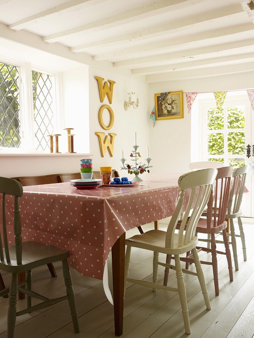 Dining room with spotted tablecloth and antique, hand-painted wooden chairs