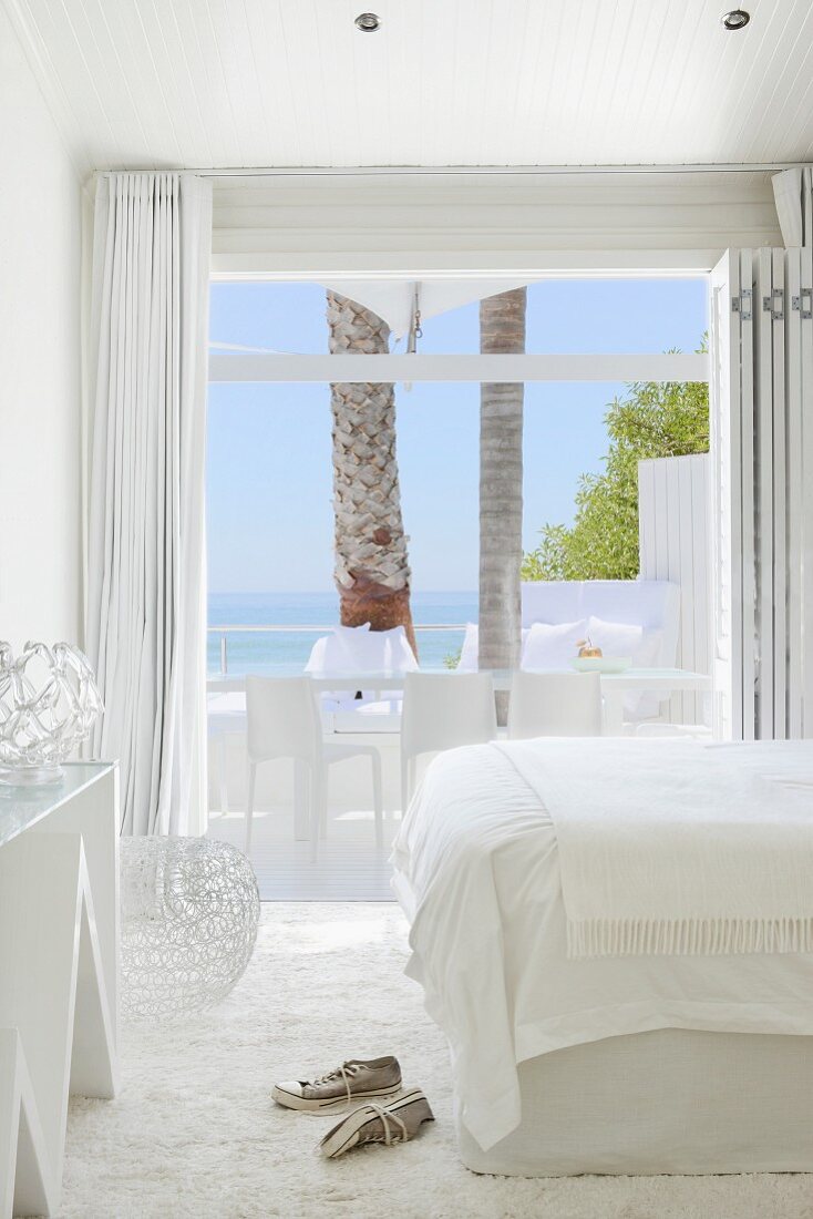 Sneakers on flokati rug in white, designer bedroom with glass wall and sea view