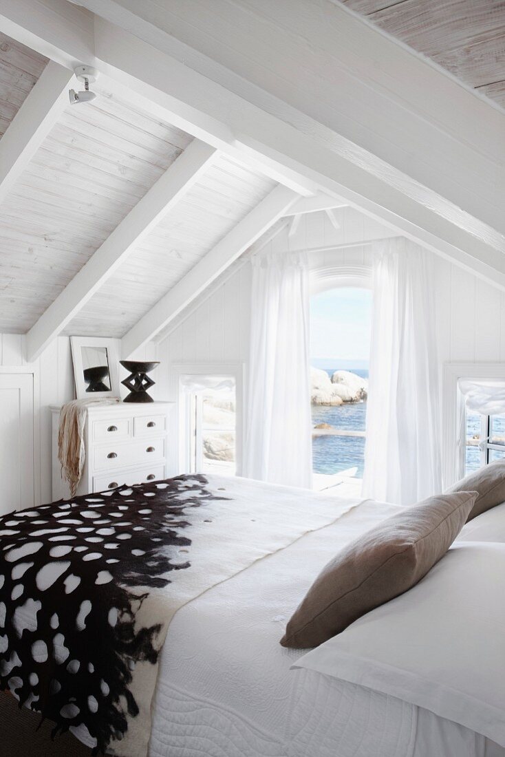 Relaxing holiday atmosphere in white bedroom with view of sea and rocks