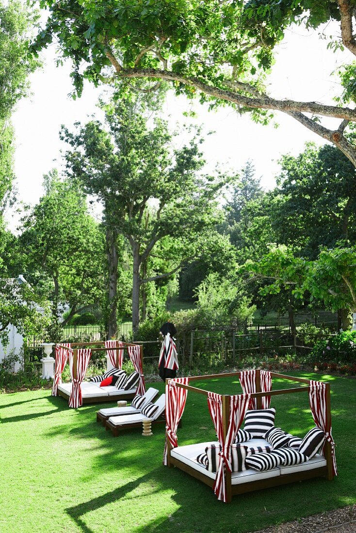Cheerful daybeds with striped textiles in well-kept garden