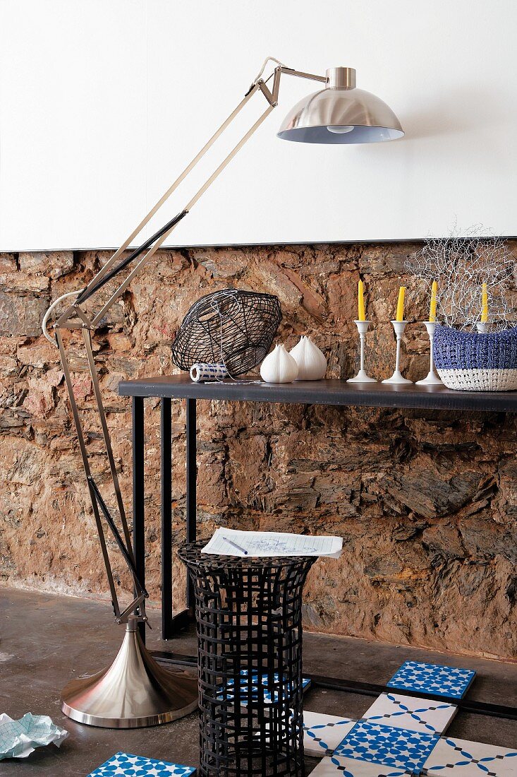 Wandtisch mit Dekogegenständen, Stehlampe aus Edelstahl, Beistelltisch aus Geflecht und Bodenfliesen im holländischen Stil