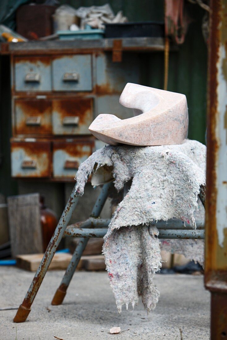 Skulpturales Objekt auf Vintage Hocker in einer Werkstatt