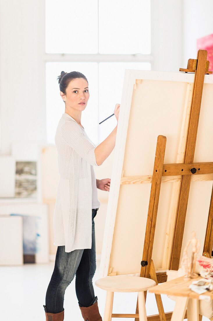 Frau malt ein Bild auf einer Staffelei im Künstleratelier