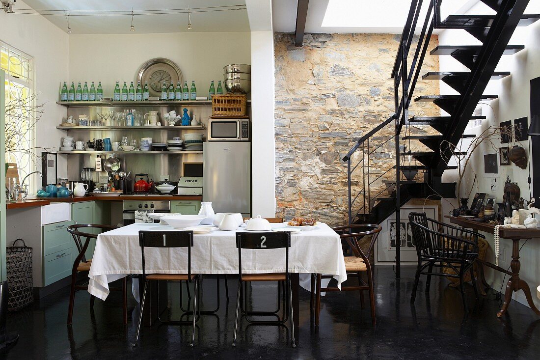 Exposed stone wall, interior staircase, kitchenette and dining table in kitchen