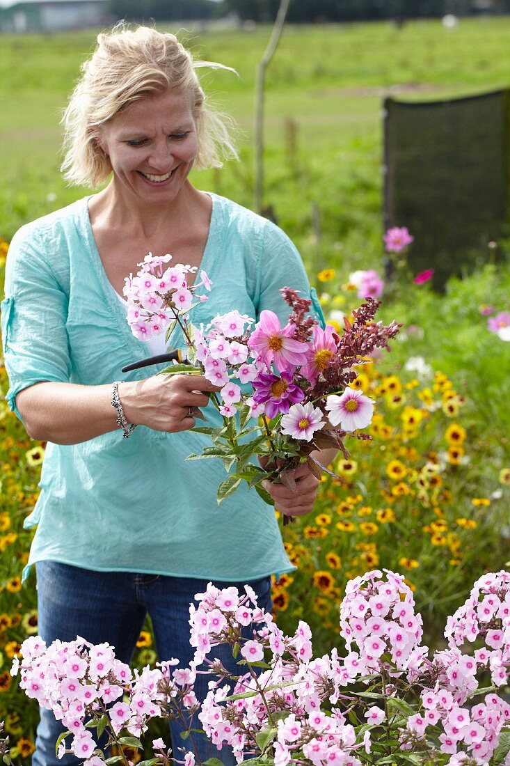 Frau pflückt Gartenblumen für einen Blumenstrauss