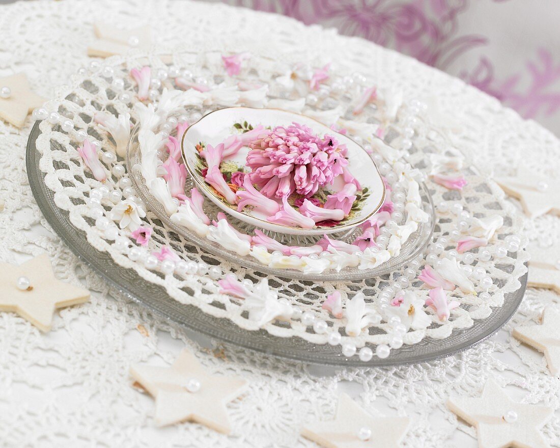 Tischdekoration mit weissen Spitzendeckchen und rosa Hyazinthenblüten