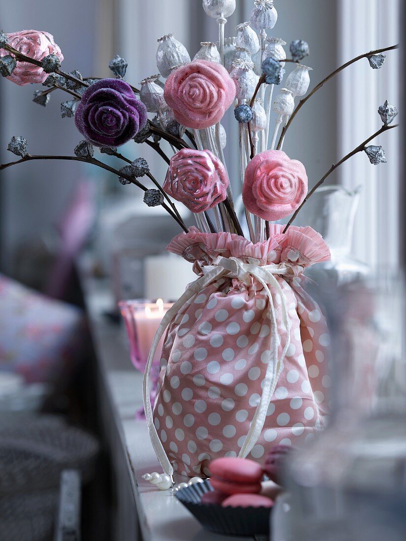 Gesteck aus künstlichen Blumen in eingepackter Vase auf Fensterbank