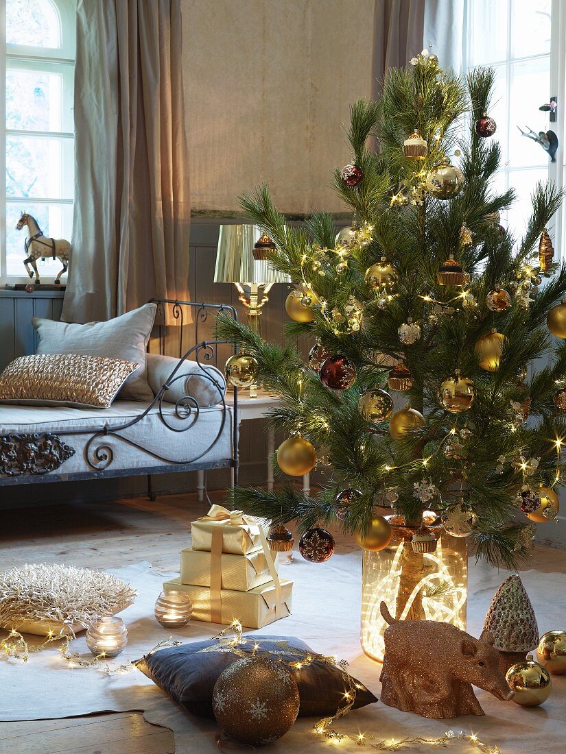 Dekorierter Weihnachtsbaum und Geschenke auf Boden vor Sitzbank mit Metallgestell in ländlichem Wohnzimmer
