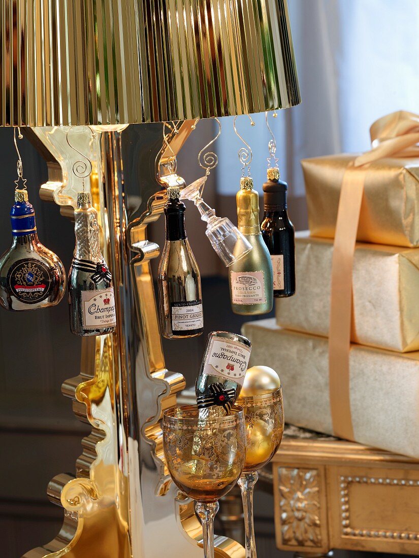 Deko Flaschen hängen am Messingschirm einer Stehleuchte neben aufgetürmten Geschenken