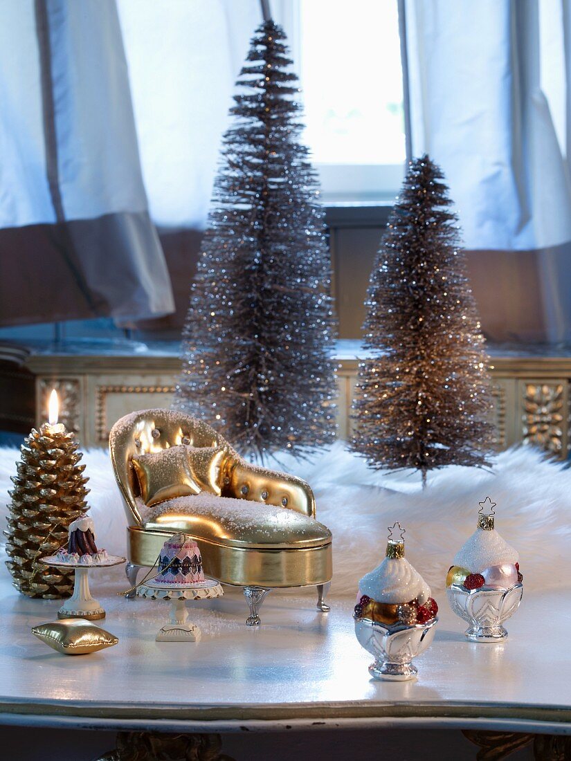 Christmas baubles and miniature gilt chaise longue in front of Christmas tree ornaments