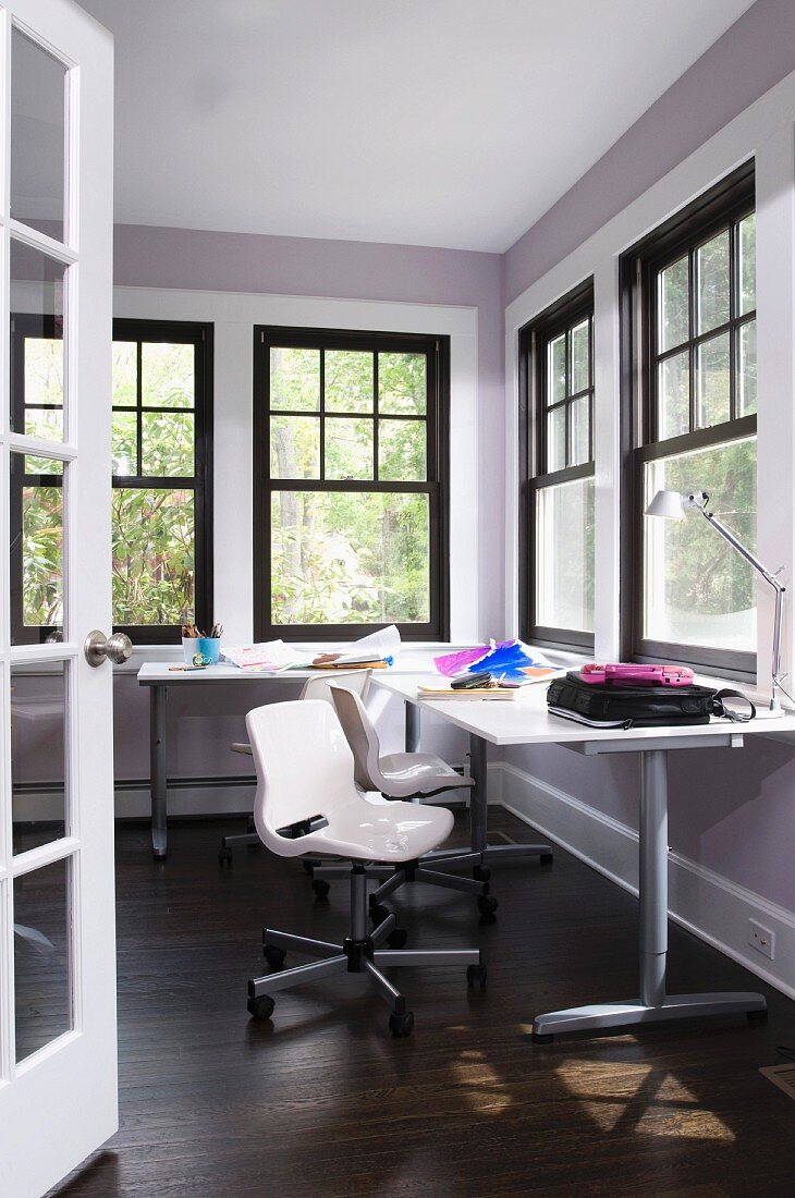 Modern workspace in corner of room with black, traditional lattice windows