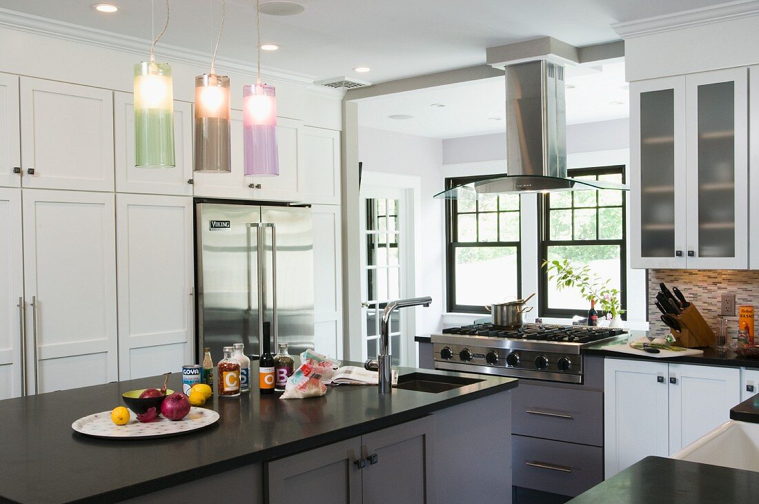 Freistehender Küchenblock unter modernen Hängeleuchten mit farbigen Glasschirmen in weisser Landhausküche