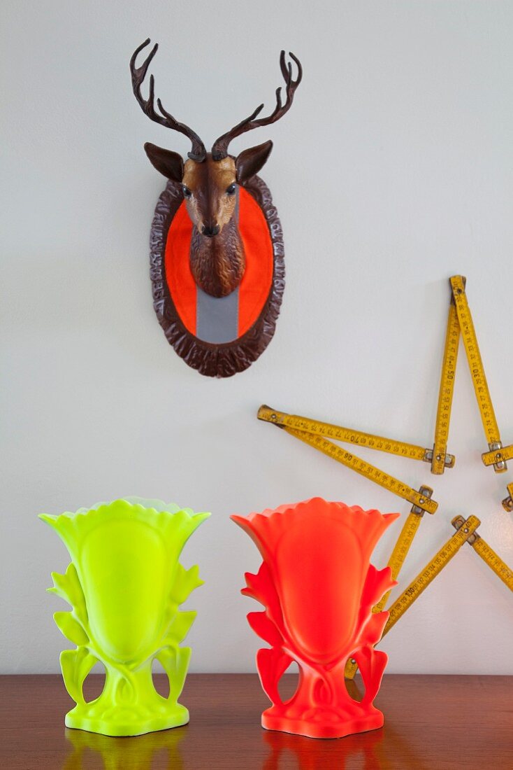 Mounted deer's head with safety-orange strips, star made from folding ruler and neon goblets