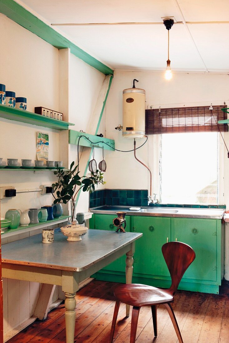 Vintage kitchen with the wood components painted green and bentwood chair at an antique table with stainless steel top