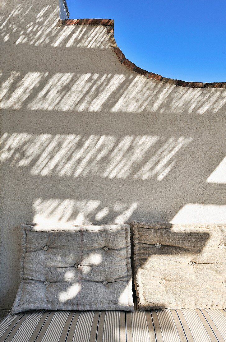 Grosse Polster auf Tagesbett an geschwungener Wand einer mediterranen Veranda