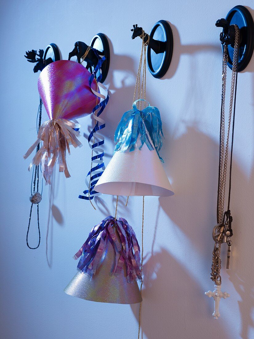 Partyhütchen mit Deko und Halsketten an Wandhaken mit Tiermotiven