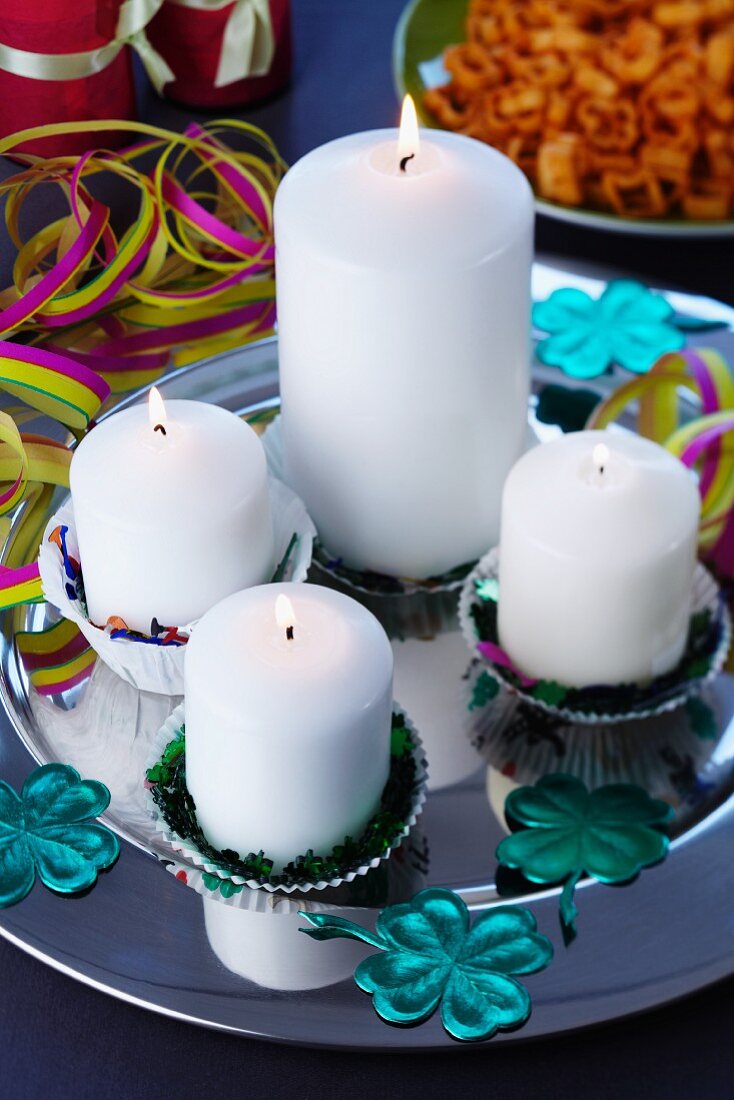 Candles in paper cake cases on silver platter with scattered table confetti
