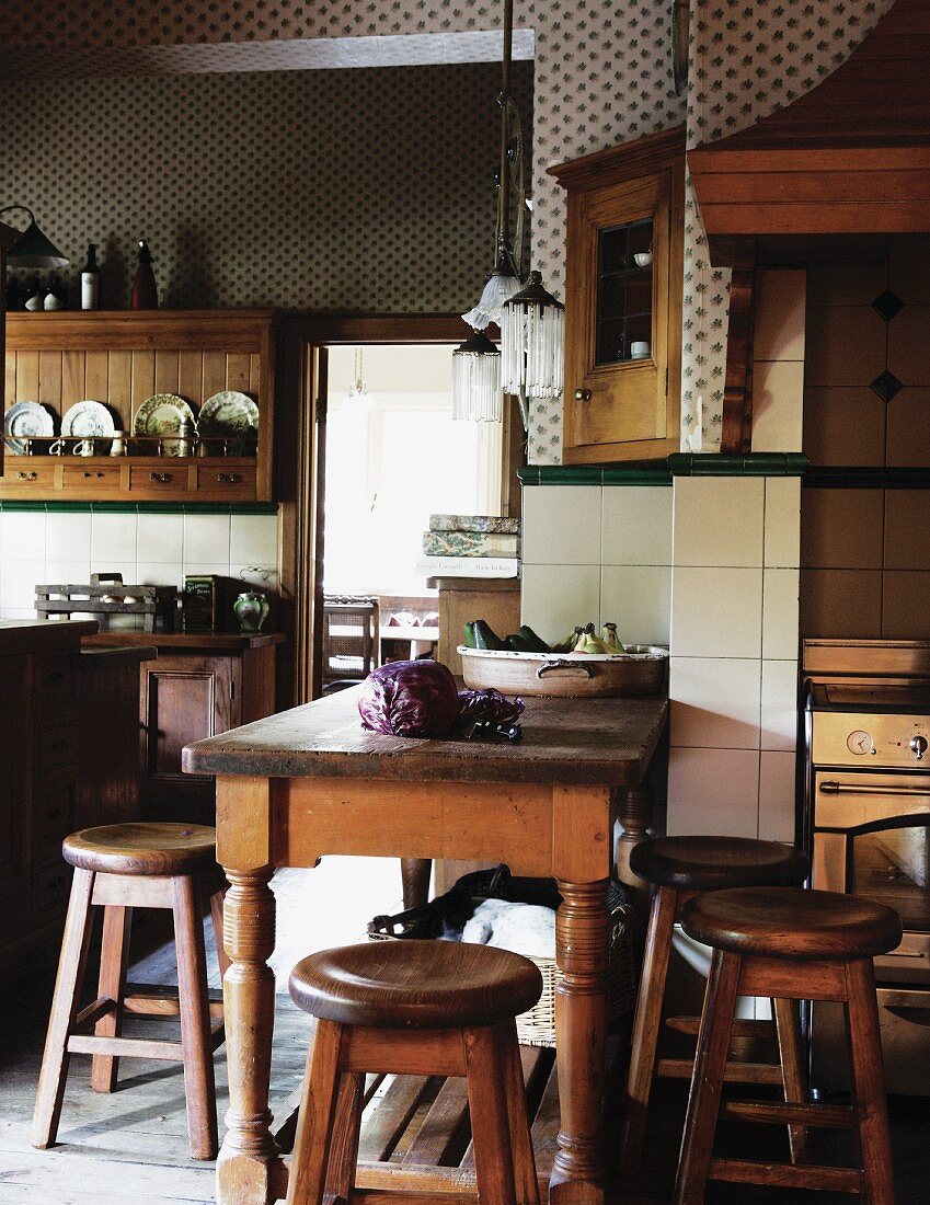 Rustikaler Holztisch und Hocker in ländlicher Küche mit weissen Wandfliesen