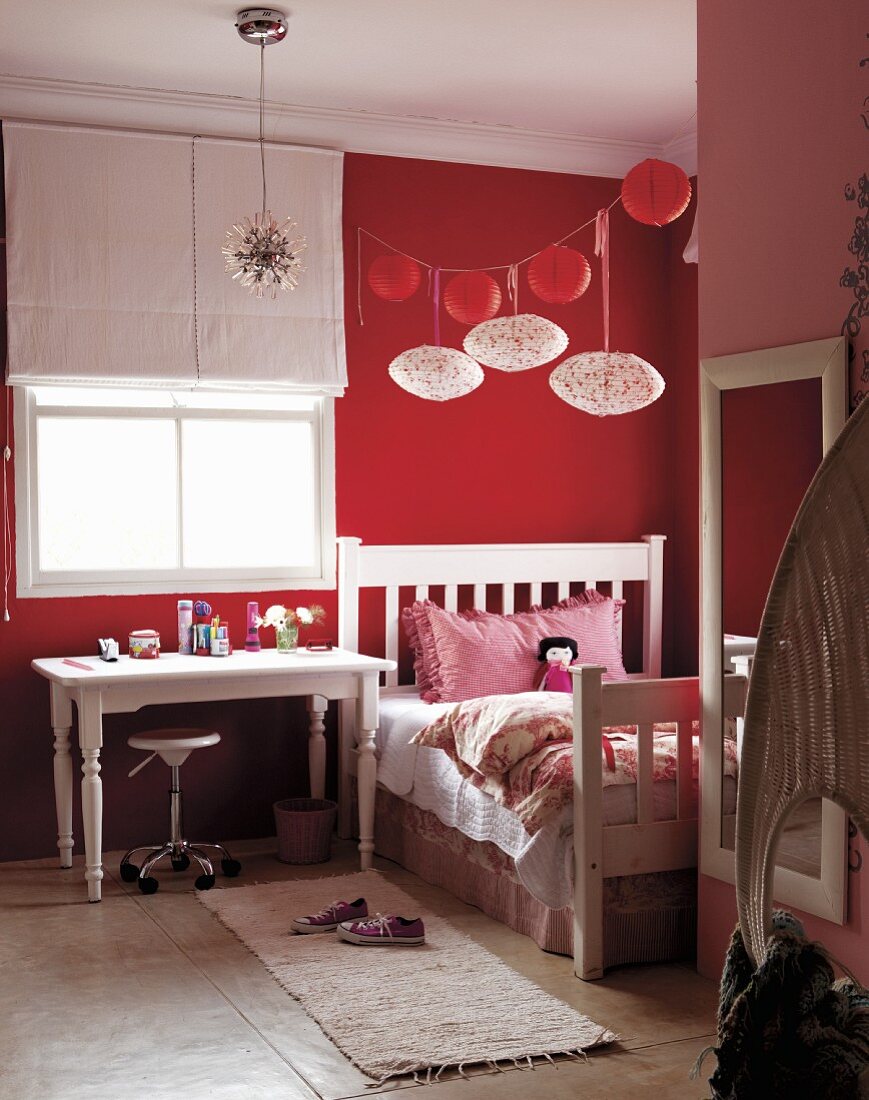 Rot-weisses Mädchenzimmer - Rote und weiße Lampions über Vintage Bett neben Arbeitstisch am Fenster mit halboffenem Rollo