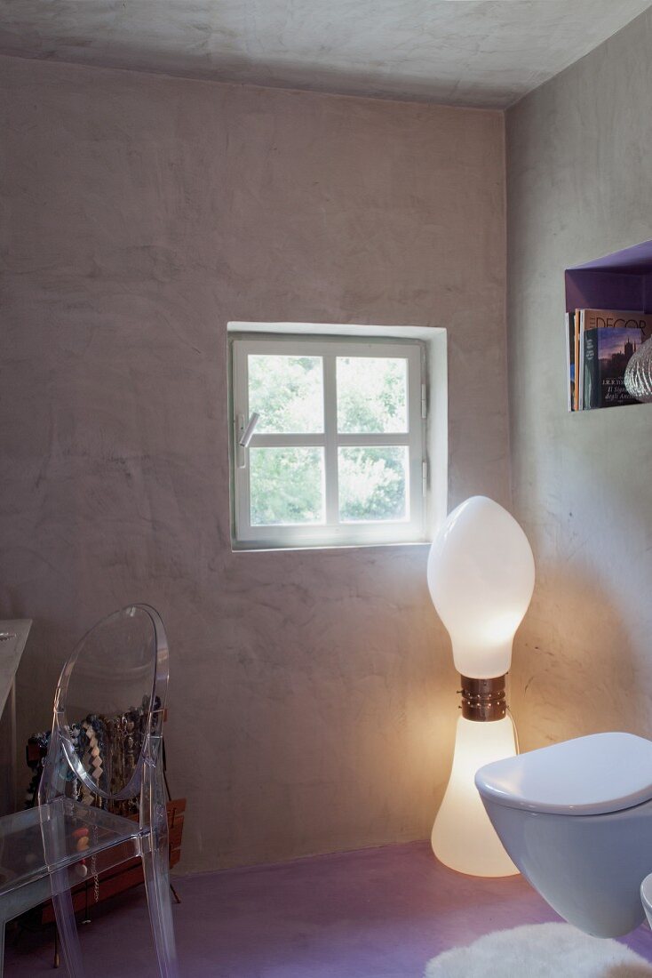 Postmodern inspiriertes Badezimmer mit Designerlampe und Plexi-Stuhl zu Betonwänden und pastellviolettem Boden