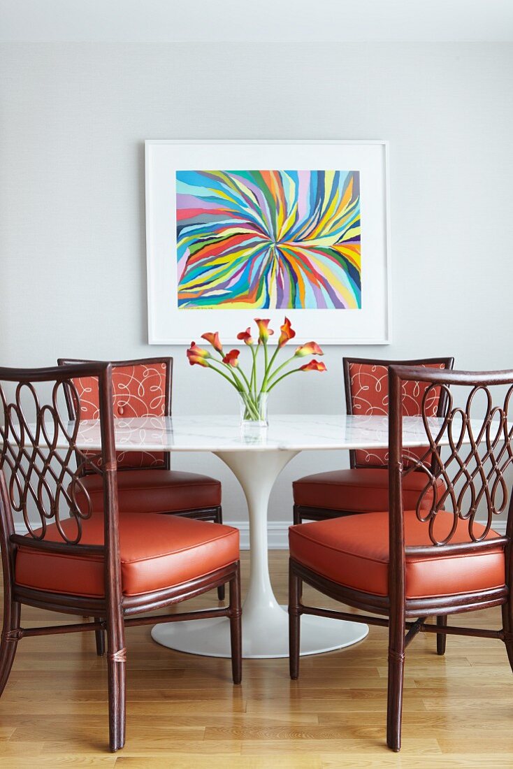 Klassiker Tisch mit Marmorplatte und Holzstühle mit rotem lederbezogenem Polster vor Wand mit modernem Bild