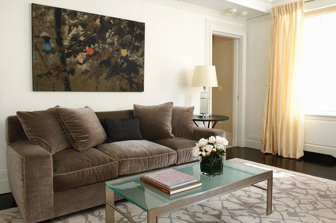 Sofa with grey velvet upholstery and glass table in classic living room