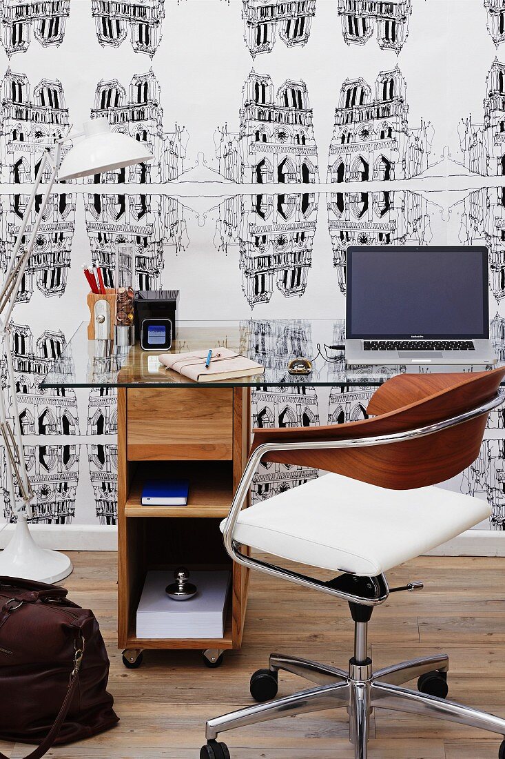 Desk and swivel chair in front of wallpapered wall