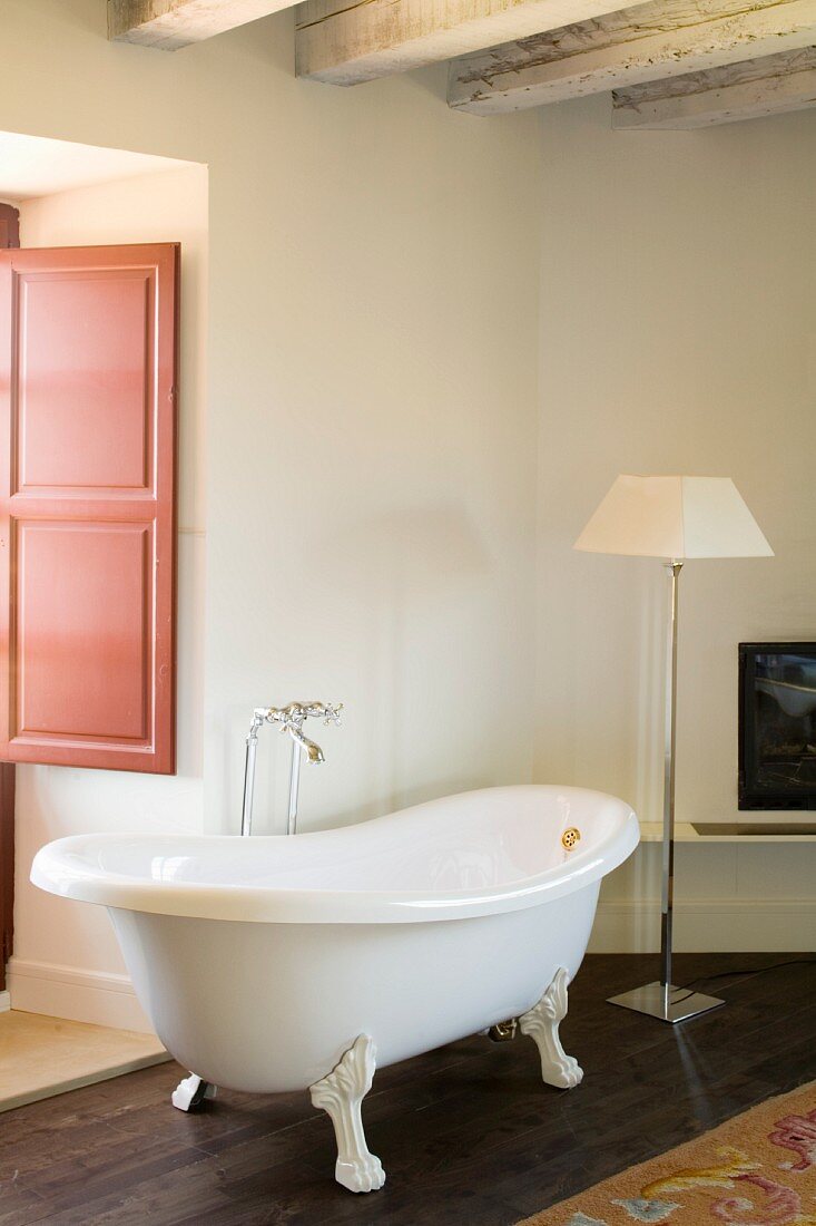 Free-standing vintage bathtub and classic standard lamp in corner of room with rustic ambiance