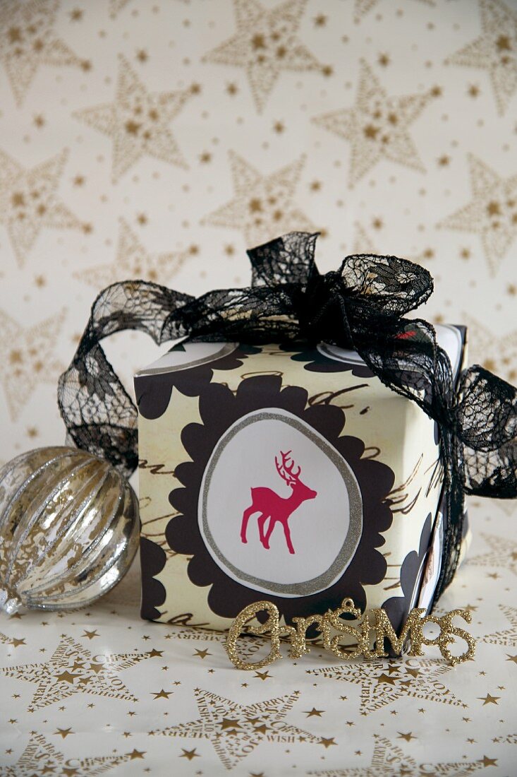 Verpacktes Weihnachtsgeschenk mit Rentiermotiv auf weißem Geschenkpapier mit goldenem Sternenmuster