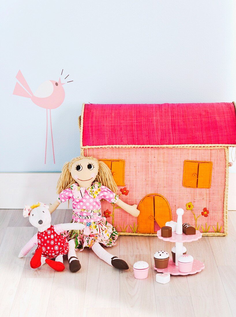Stoffpuppen mit bunten Kleidern vor einem Puppenhaus