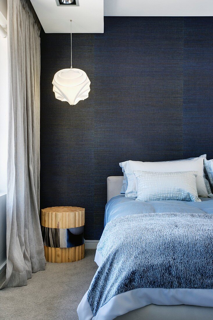 Doppelbett vor nachtblau schimmernder Textiltapete