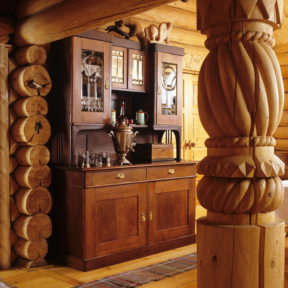 Turned wooden column in doorway with view of antique kitchen dresser in living-dining room of log cabin