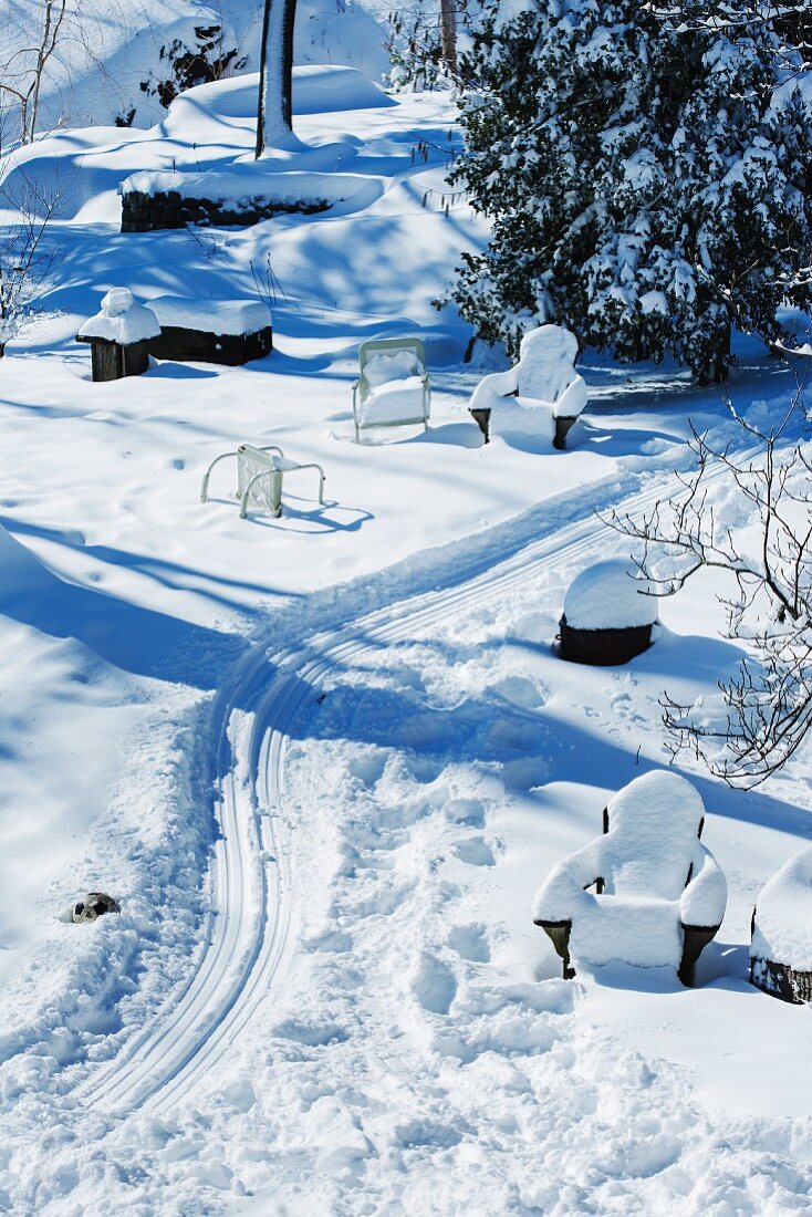 Rodelbahn und schneebedeckte Sitzmöbel im Garten