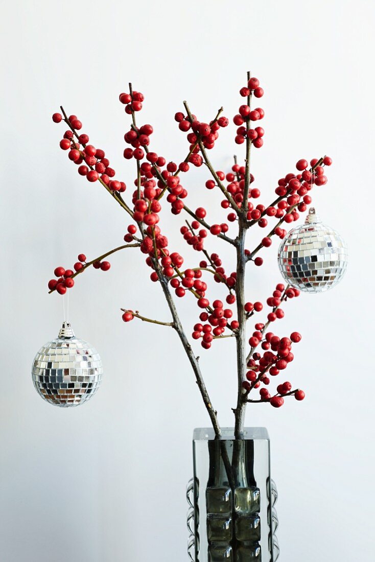 Mosaic mirrored disco balls hanging on festive holly branches with red berries