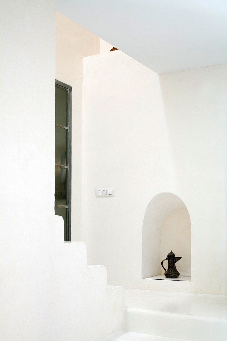 Treppenaufgang als minimalistische, weiße Raumskulptur mit orientalischer Teekanne in Mauernische