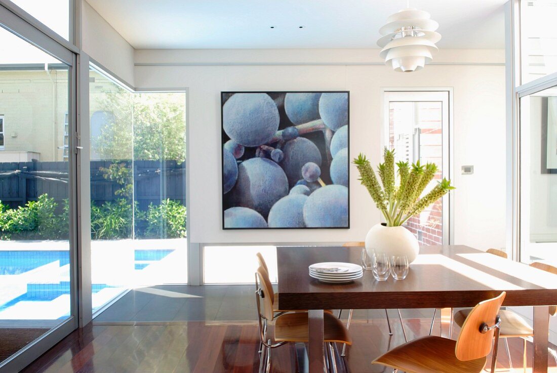 Verglaster Essraum mit Blick auf Gartenpool, im Hintergrund Bild mit Weintrauben