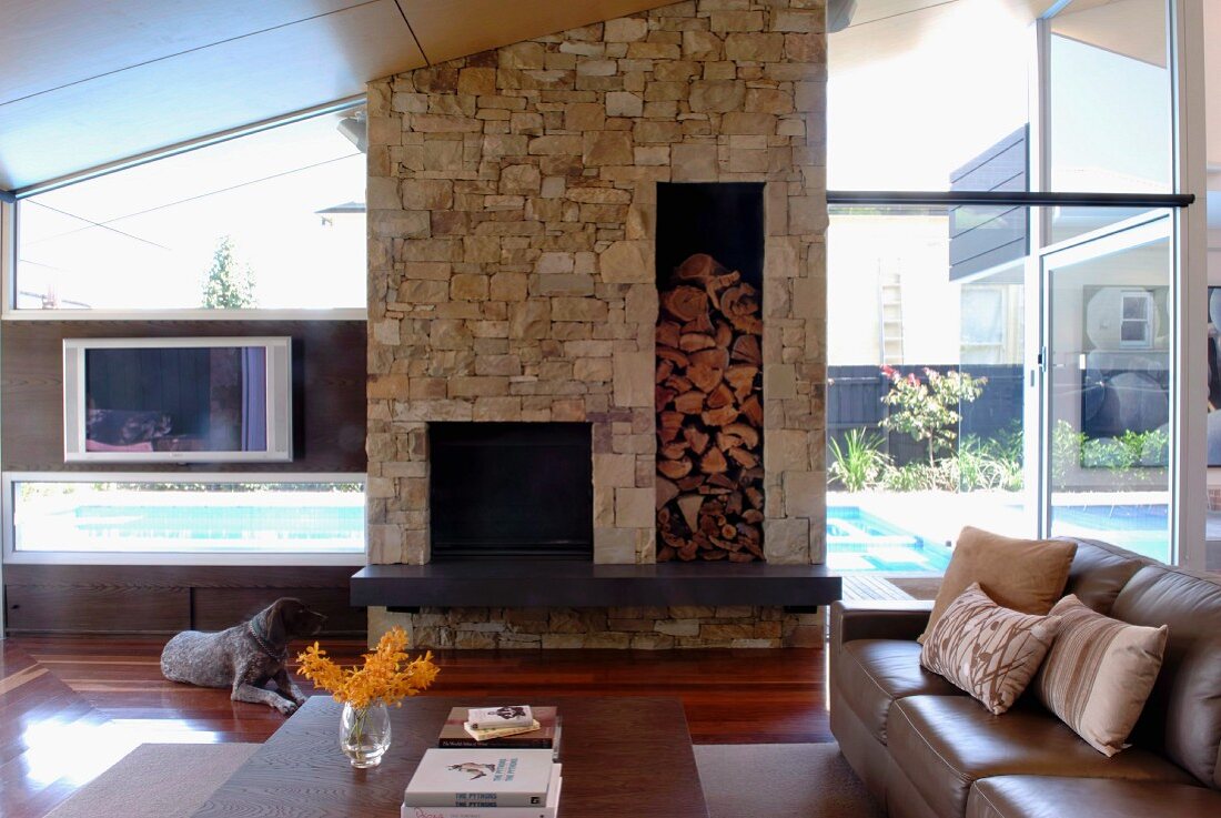 High-ceilinged interior with stone chimney breast in contemporary glass house