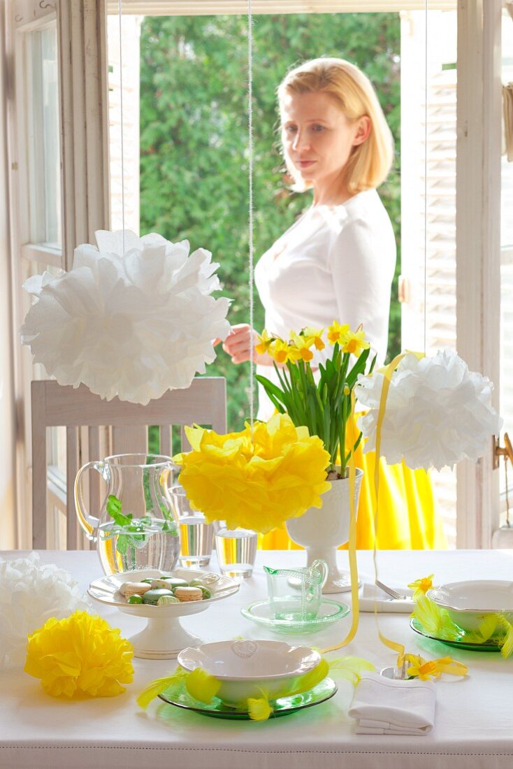 A woman looking at a table laid for Easter celebrations, with narcissi and pompoms