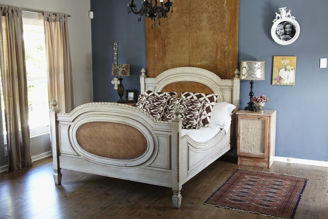 Antique double bed in front of wall hanging on blue-painted wall in elegant, vintage bedroom