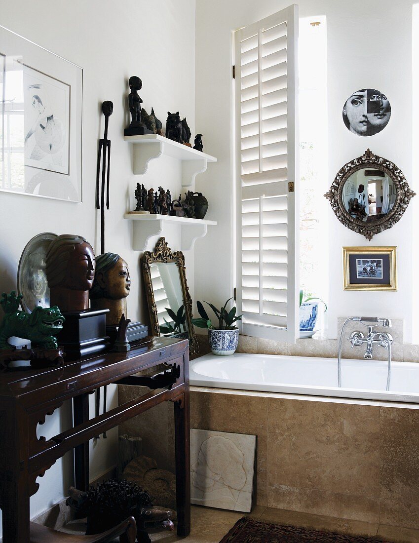 Eine Sammlung von Büsten, Figuren und Spiegeln auf Konsolentisch und Wandborden über einer Badewanne