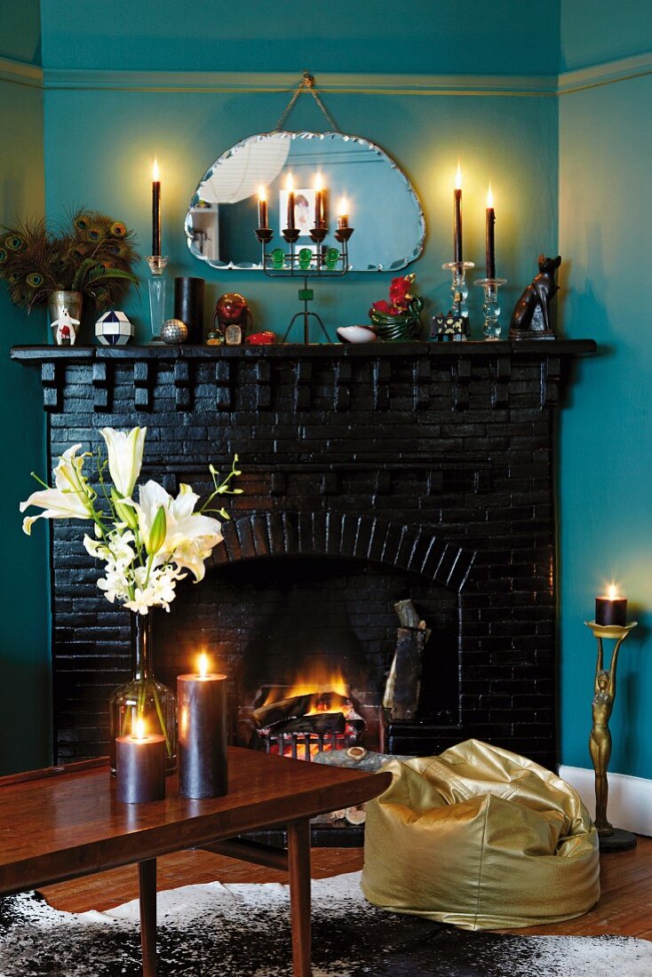 Romantische Kerzenstimmung mit goldenem Sitzsack und dunkel lackierten Backsteinkamin zu blau getönter Wand