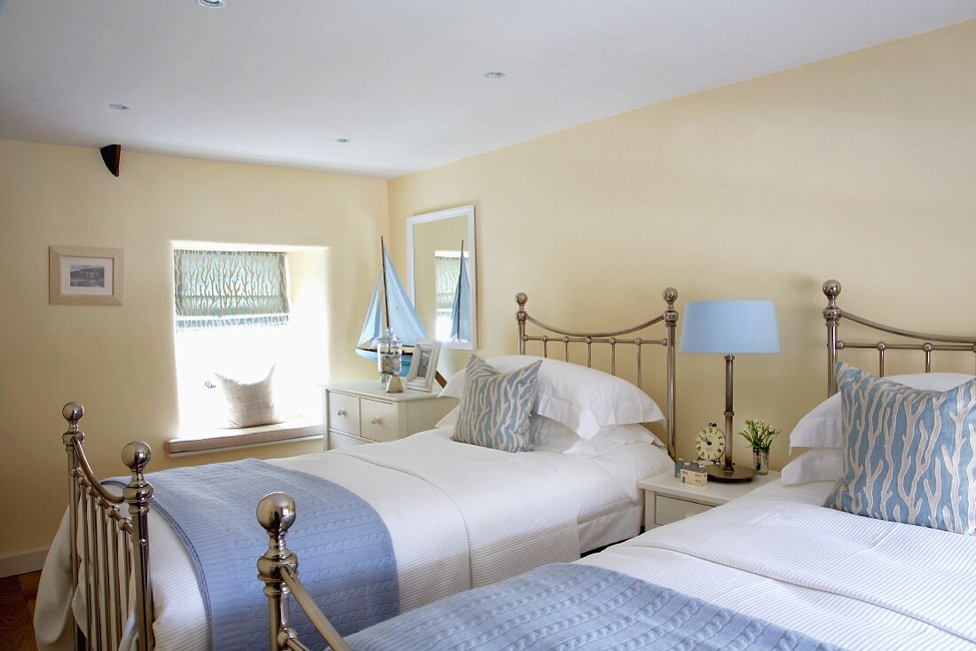 Cremefarbenes Schlafzimmer mit hellblauen Accessoires zu verchromten Landhausbetten