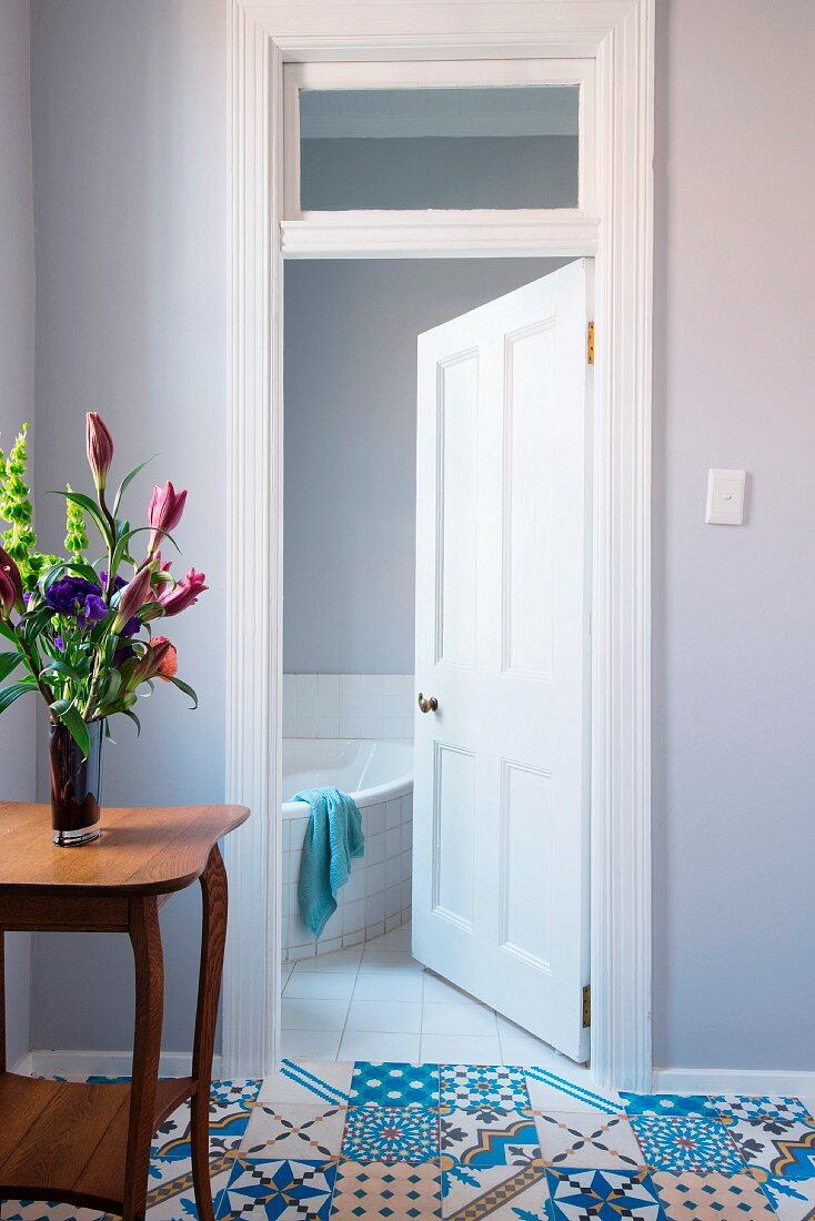 Blick durch geöffnete Kassettentür ins Badezimmer; Im Vorraum Bodenfliesen mit orientalischer Musterung