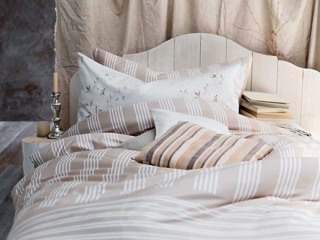 Französisches Bett mit Kopfteil aus Holz und Bettwäsche in verschiedenen Brauntönen